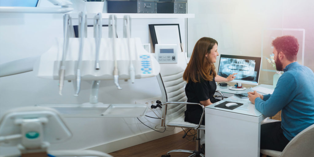 dentist discussing digital scans of mouth with dental patient at desk